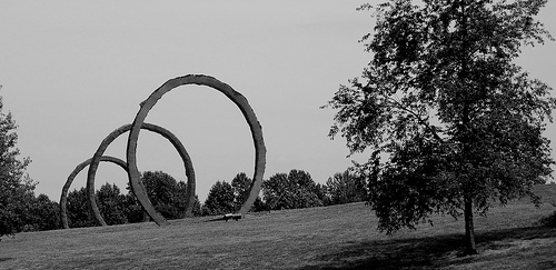 An art installation, showing three large rings standing in a field.