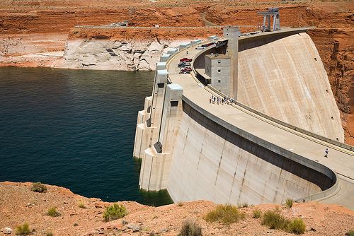 Cars parked along the top of a dam, and a large reservoir of water.